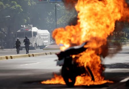 Riot security forces look on as a motorcycle bursts into flames during a rally against Venezuela's President Nicolas Maduro's government in Caracas, Venezuela, August 4, 2017. REUTERS/Ueslei Marcelino