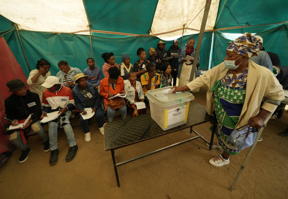 An elderly woman cast her vote as party agents observe at a polling station in Maseru, Lesotho, Friday, Oct. 7, 2022. Voters across the picturesque mountain kingdom of Lesotho are heading to the polls. (AP Photo/Themba Hadebe)