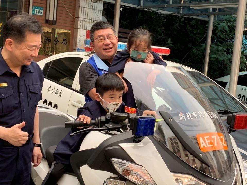 《圖說》新北市議會副議長陳鴻〈右〉與永和分局長王耀輝抱起小朋友體驗騎警用重型機車。〈永和分局提供〉