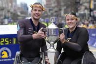 Marcel Hug, of Switzerland, left, winner of the Boston Marathon men's wheelchair division, and Eden Rainbow Cooper, of Britain, right, winner of the women's wheelchair division, display the trophy on the finish line of the Boston Marathon, Monday, April 15, 2024, in Boston. (AP Photo/Steven Senne)