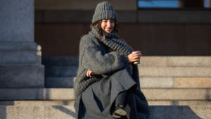 Inspiration: Benthe Liem sitting drinking coffee wears grey beanie, knit, scarf, skirt, black Prada bag outside Marimekko during the Copenhagen Fashion Week AW24 on February 01, 2024 in Copenhagen, Denmark. (Photo by Christian Vierig/Getty Images)