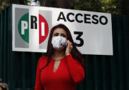 Nallely Gutierrez, leader of the Institutional Revolutionary Party of Mexico, PRI, speaks on a mobile phone outside the locked PRI headquarters in Mexico City, on Wednesday, June 30, 2021. The doors were closed after party dissidents set up a ring of protesters Tuesday around the headquarters and fighting apparently broke out when a squad of loyalists tried to retake the building. (AP Photo/Marco Ugarte)