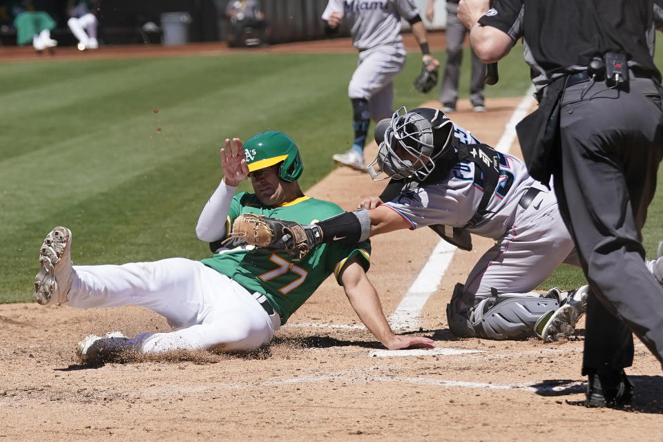 Oakland Athletics' Jonah Bride, left, is tagged out at home by Miami Marlins catcher Nick Fortes during the sixth inning of a baseball game in Oakland, Calif., Wednesday, Aug. 24, 2022. (AP Photo/Jeff Chiu)