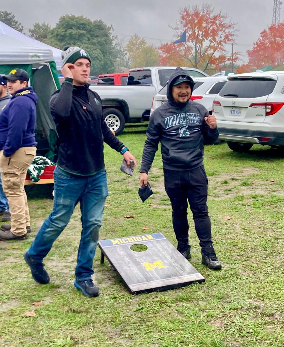 Michigan State fans Matt Wilson and JP Tongson play cornhole while tailgating.  Tongson is part of the MSU College of Osteopathic Medicine, but, apart from his white coat ceremony, this is his first time in East Lansing. He was glad to experience the atmosphere on game day.