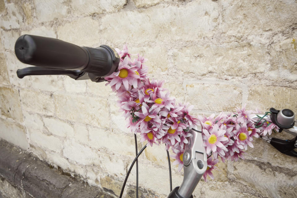 An arrangement of flowers on handlebar of a bicycle.
Beautiful  bicycle, resting on wall; vintage style.