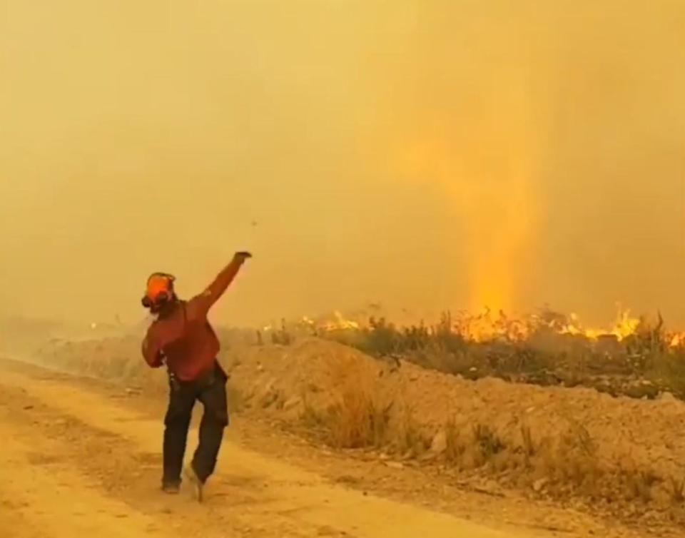 A firefighter frustratedly hurls a rock at the flames as they lose the battle with the firenado. (BC Wildfire Services)