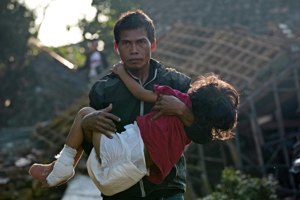 A man carries his injured daughter as they head to a temporary shelter for those displaced by Monday's earthquake in Cianjur, West Java, Indonesia, Thursday, Nov. 24, 2022. The 5.6 magnitude earthquake left hundreds dead, injures and missing as buildings crumbled and terrified residents ran for their lives on Indonesia's main island of Java. (AP Photo/Tatan Syuflana)
