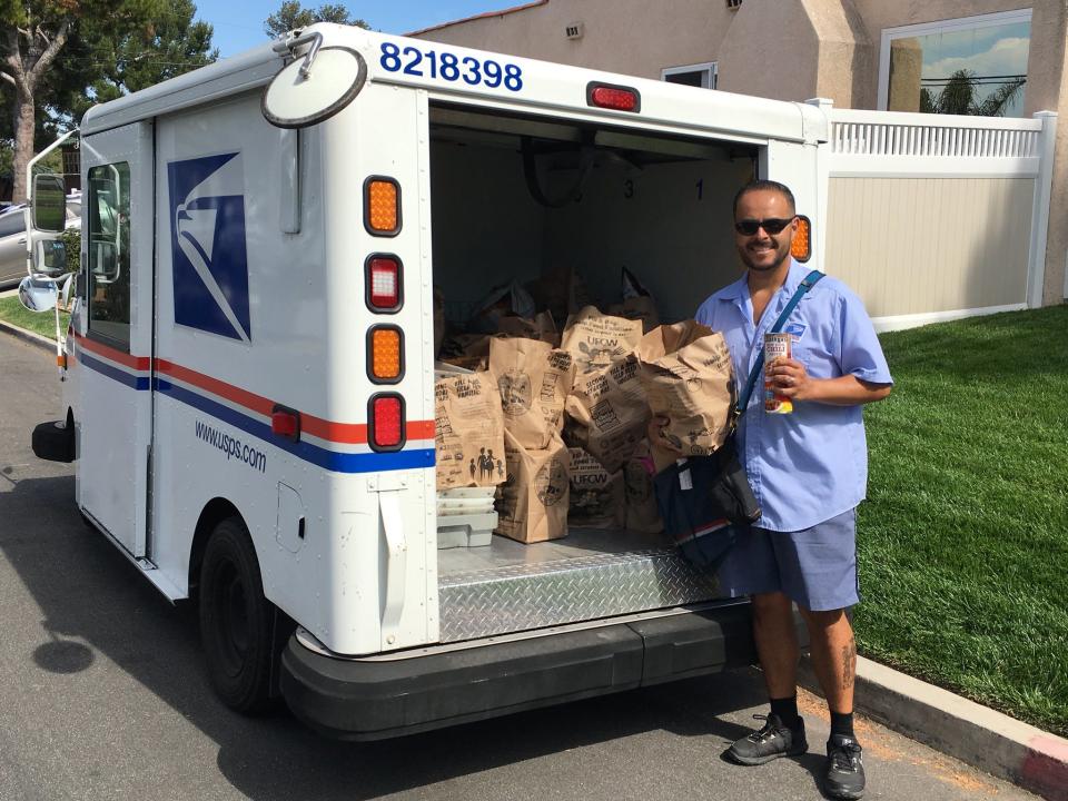 A letter carrier with the U.S. Postal Service loads a delivery truck with donations of food collected through the National Association of Letter Carriers' annual National Stamp Out Hunger Food Drive.
