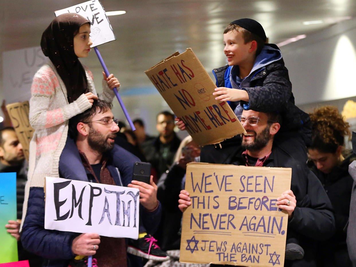 Yildirim, 7, left, sits on her father, Fatih, of Schaumburg, and Adin Bendat-Appell, 9, right, sits on his father, Rabbi Jordan Bendat-Appell, of Deerfield, during a protest at O'Hare International Airport in Chicago: Getty