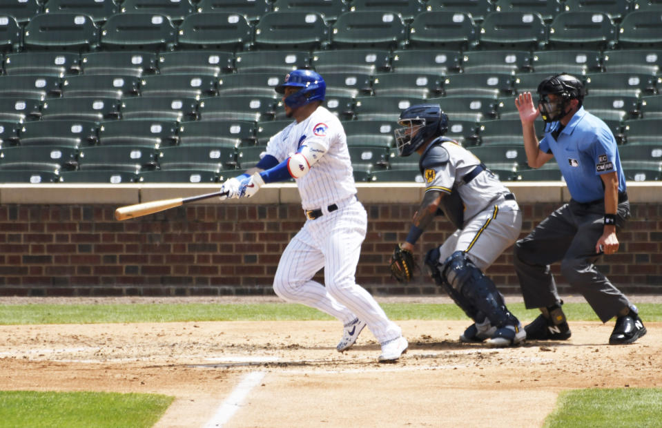 Chicago Cubs' Willson Contreras, left, hits a one-run double against the Milwaukee Brewers during the fourth inning of a baseball game Sunday, July, 26, 2020, in Chicago. (AP Photo/David Banks)