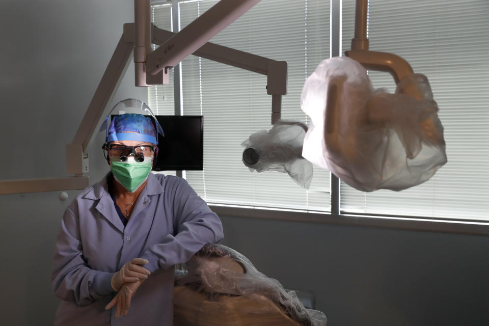 Dr. Terri Tiersky poses for a portrait in full personal protective equipment, double mask, face shield, gown and gloves, at her dentist office in Skokie, Ill., on Friday, June 12, 2020. Tiersky closed her office to all but emergencies in mid-March. She then helped arrange donations of personal protective equipment from the Chicago Dental Society for health workers treating COVID-19 patients. (AP Photo/Charles Rex Arbogast)