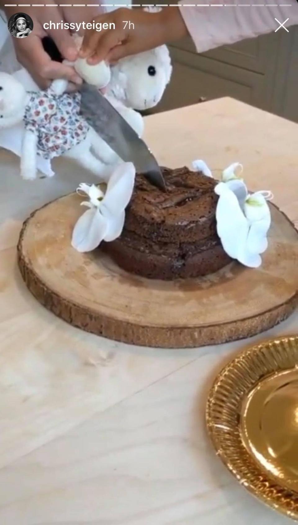 Chloe and Nosh cut their tiered chocolate brownie cake. (Photo: Chrissy Teigen / Instagram)