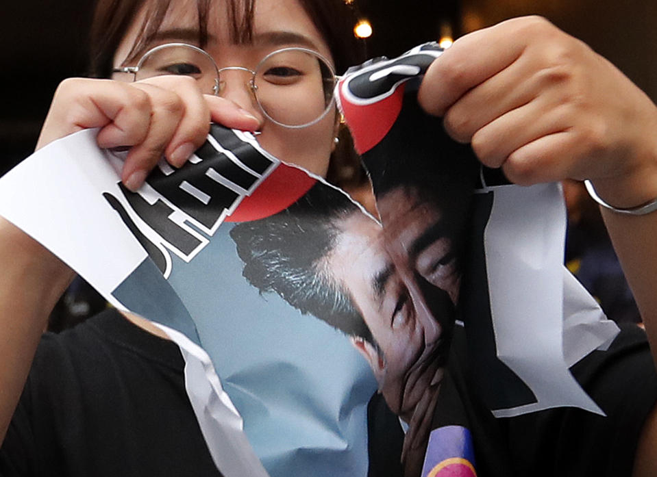 A protester tears an image of Japanese Prime Minister Shinzo Abe during a rally denouncing Japanese government's decision on their exports to South Korea, in front of the Japanese embassy in Seoul, South Korea, Thursday, July 18, 2019. (AP Photo/Ahn Young-joon)