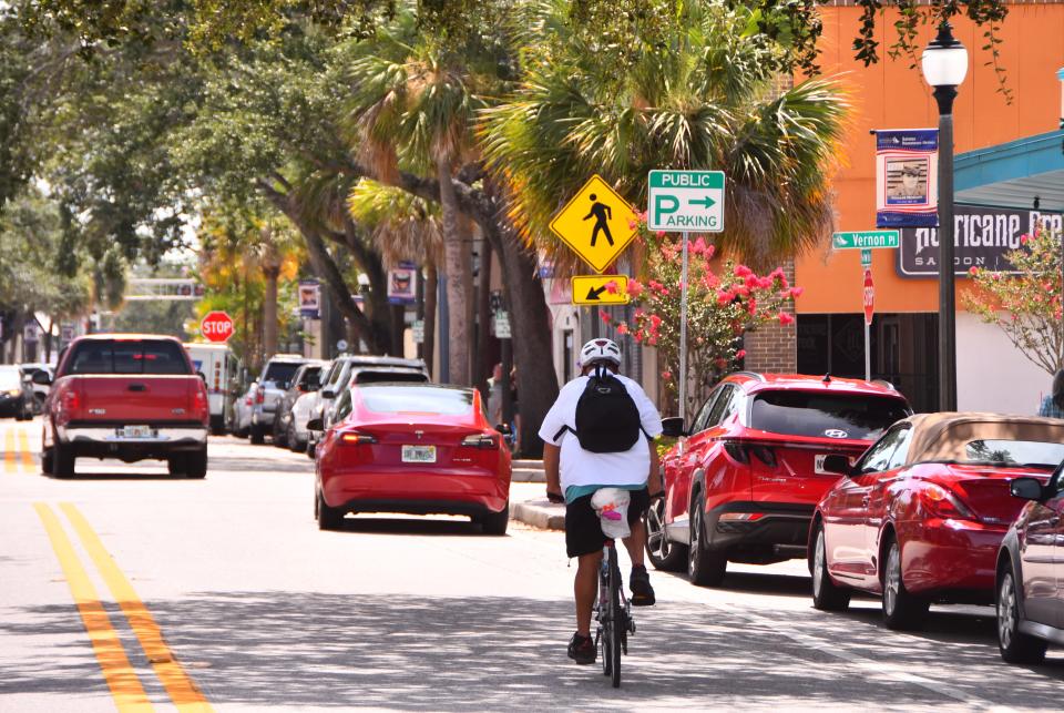 A bicyclist pedals eastward down New Haven Avenue approaching Vernon Place in downtown Melbourne.