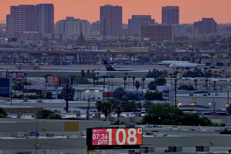 FILE - A sign displays an unofficial temperature as jets taxi at Sky Harbor International Airport at dusk, July 12, 2023, in Phoenix. The toll of heat associated deaths still being tallied after the hottest summer ever in Arizona’s most populous county has now soared over 360, alarming public health officials. (AP Photo/Matt York, File)