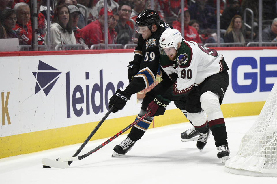 Arizona Coyotes defenseman J.J. Moser (90) battles Washington Capitals center Aliaksei Protas (59) for the puck during the first period of an NHL hockey game, Saturday, Nov. 5, 2022, in Washington. (AP Photo/Nick Wass)