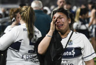 Fans of Gimnasia de La Plata react to tear gas on the field during a local tournament match between Gimnasia de La Plata and Boca Juniors in La Plata, Argentina, Thursday, Oct. 6, 2022. The match was suspended after tear gas thrown by the police outside the stadium wafted inside affecting the players as well as fans who fled to the field to avoid its effects. (AP Photo/Gustavo Garello)