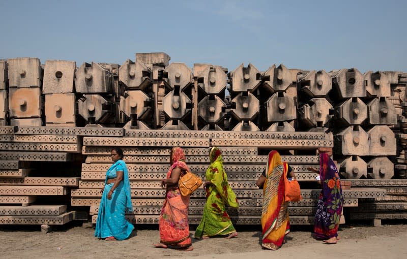 Devotees walk past the pillars that Hindu nationalist group Vishva Hindu Parishad (VHP) say will be used to build a Ram temple at the disputed religious site in Ayodhya