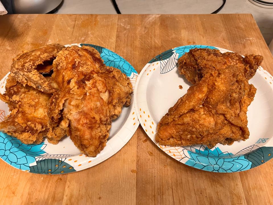 Two white and blue plates of fried chicken on wooden cutting board