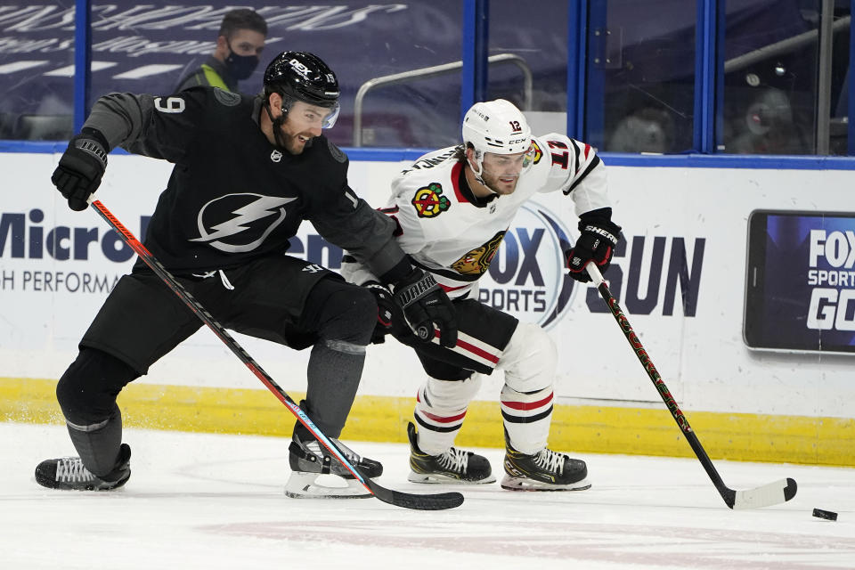 Tampa Bay Lightning right wing Barclay Goodrow (19) and Chicago Blackhawks left wing Alex DeBrincat (12) battle for the puck during the second period of an NHL hockey game Saturday, March 20, 2021, in Tampa, Fla. (AP Photo/Chris O'Meara)