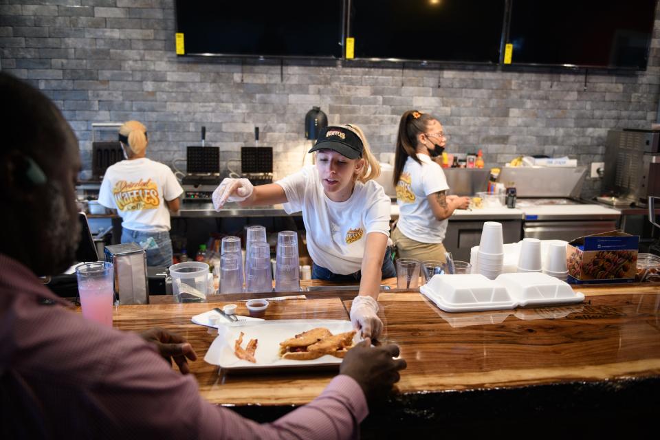 Courtney Hanson slides an order to a customer at Drizzled Waffles and Coffee restaurant at 3061 North Main St. in Hope Mills.