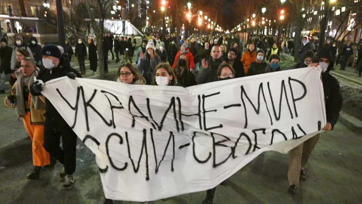 Young demonstrators march with a makeshift banner that reads, in Russian: Ukraine &#x002014; peace, Russia &#x002014; freedom.