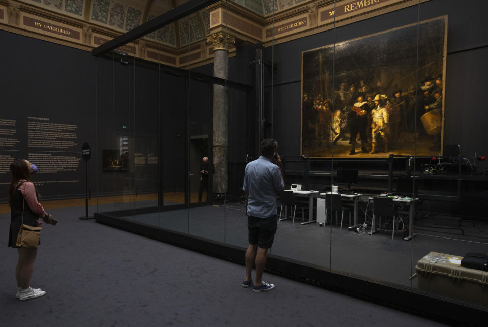 Visitors admire Rembrandt's Night Watch in the reopened Rijksmuseum in Amsterdam, Netherlands, Monday, June 1, 2020. The Dutch government took a major step to relax the coronavirus lockdown, with bars, restaurants, cinemas and museums reopening under strict conditions. (AP Photo/Peter Dejong)