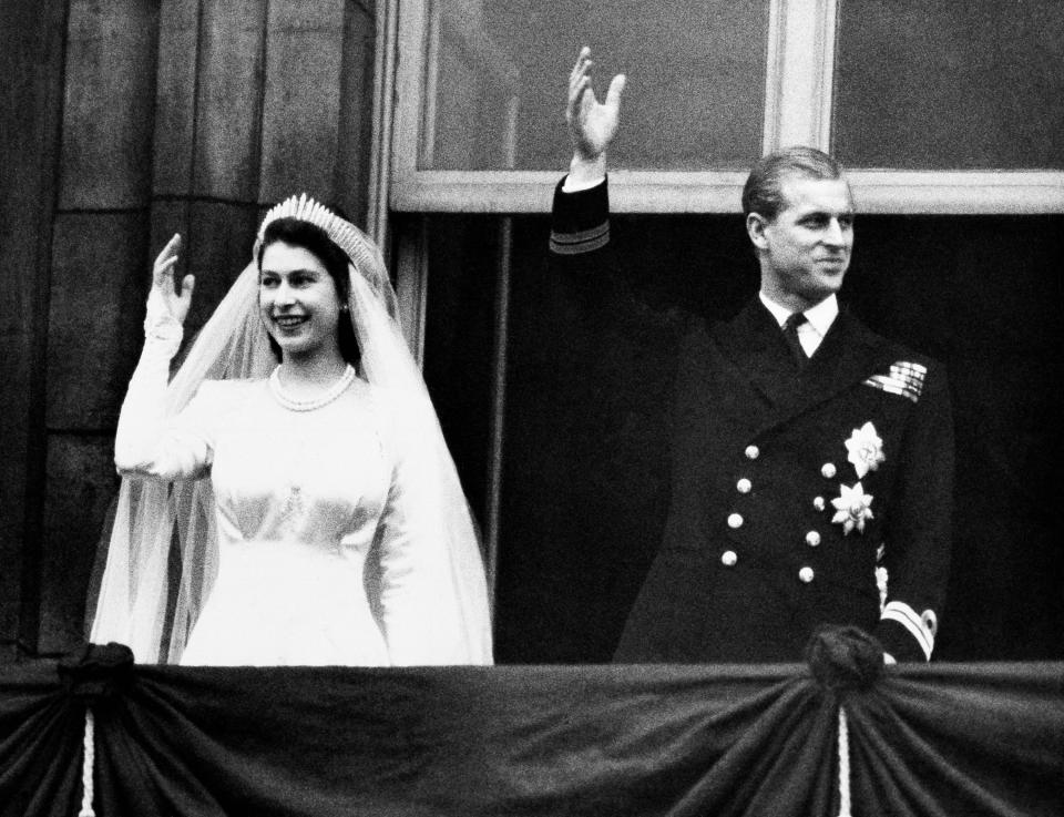 ARCHIVO - En esta foto del 20 de noviembre de 1947, la princesa Isabel de Inglaterra y su esposo, el duque de Edimburgo, saludan a la multitud en el día de su boda, desde el balcón del Palacio de Buckingham, en Londres. (AP Foto/Archivo)