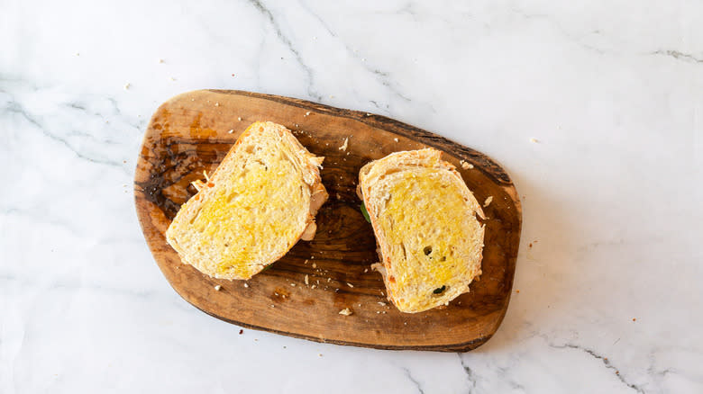 Two closed sandwiches on cutting board