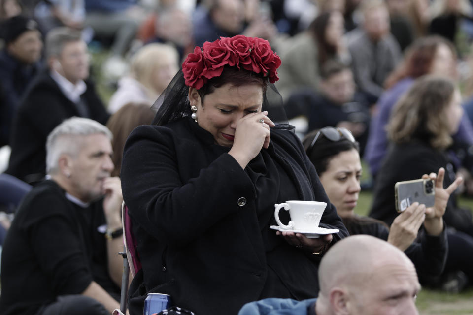 A woman reacts in Hyde Park while watching the State Funeral Service of Britain's Queen Elizabeth II on giant screens, Monday, Sept. 19, 2022 in London. (AP Photo/Lewis Joly)