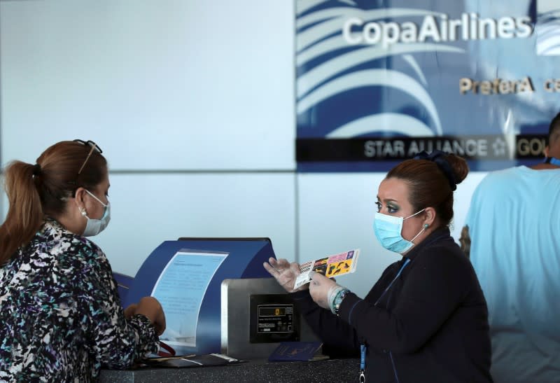 A Copa Airlines employee, wearing a protective mask, talks to a passenger at Tocumen International Airport after the Panamanian government restricted flights in recent days due to the coronavirus disease (COVID-19) outbreak, in Panama City