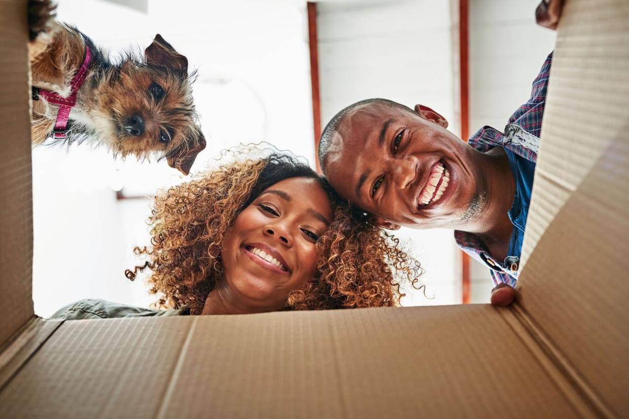 couple and their dog looking a box that arrived with their dog subscription