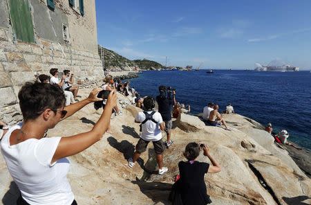 People takes pictures abd watch the cruise liner Costa Concordia during the refloat operation maneuvers at Giglio Island July 23, 2014. REUTERS/ Max Rossi