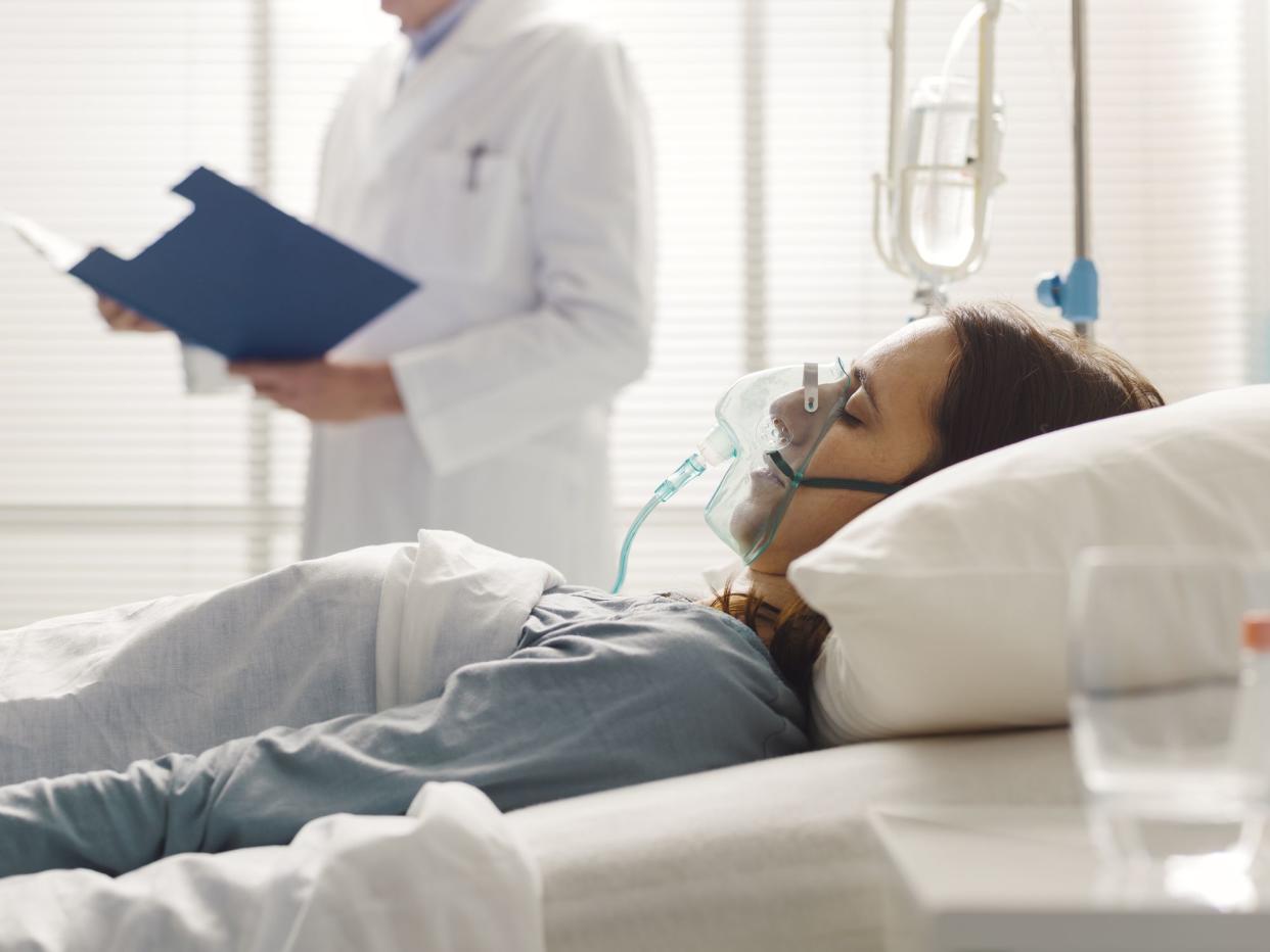 Professional doctor assisting a patient lying in bed at the hospital, he is checking medical records