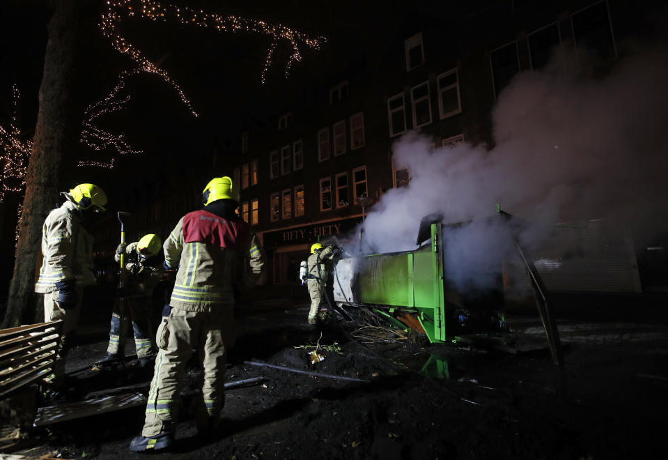 A firefighter extinguishes a a container that was set alight during protests against a nation-wide curfew in Rotterdam, Netherlands, Monday, Jan. 25, 2021. The Netherlands Saturday entered its toughest phase of anti-coronavirus restrictions to date, imposing a nationwide night-time curfew from 9 p.m. until 4:30 a.m. in a bid to control the COVID-19 infection rate. (AP Photo/Peter Dejong)