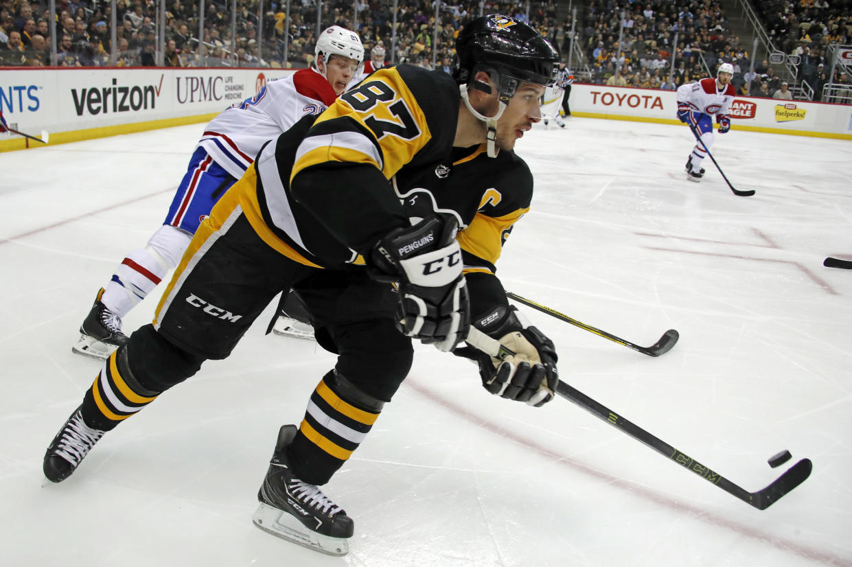 Pittsburgh Penguins’ Sidney Crosby (87) makes a pass out of the corner with Montreal Canadiens’ Mike Reilly (28) defending during the second period of an NHL hockey game in Pittsburgh, Wednesday, March 21, 2018. (AP Photo/Gene J. Puskar)