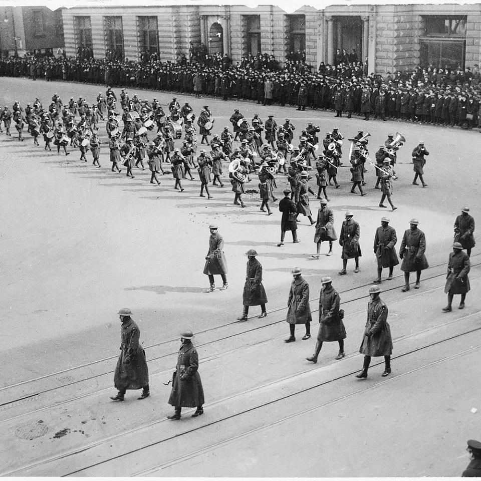 A black and white historical photo depicting a band and military personnel in formation.