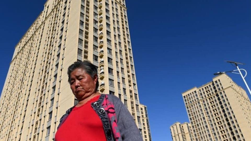 Una mujer pasa junto a unos rascacielos en Pekín