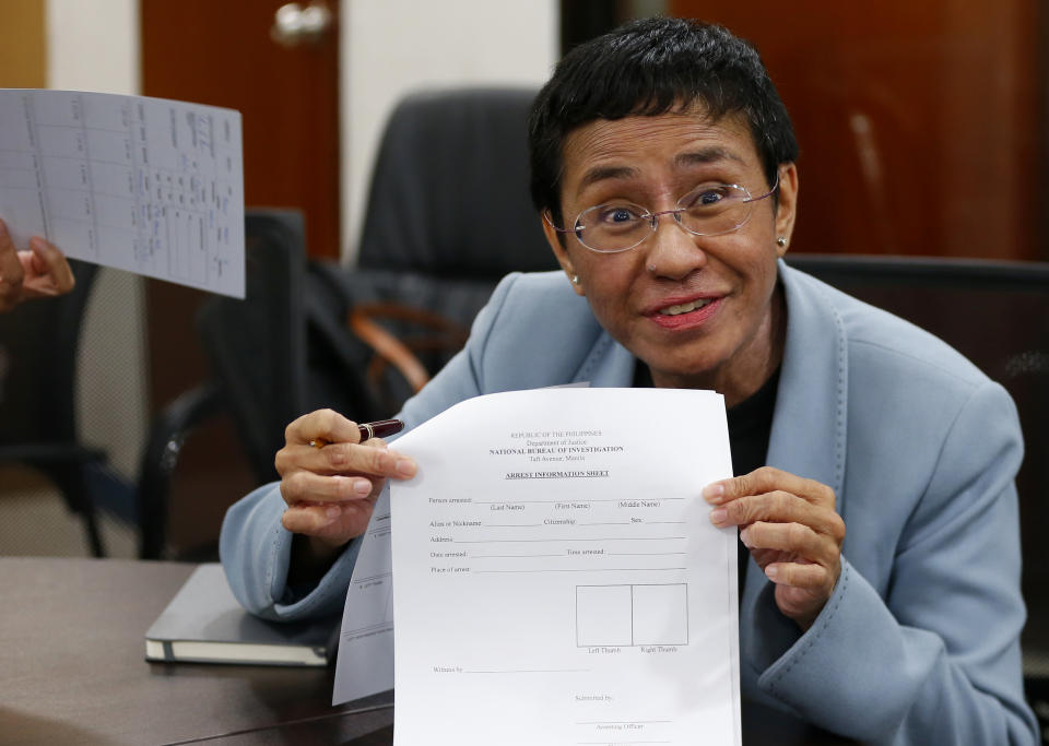 Maria Ressa, the award-winning head of a Philippine online news site Rappler that has aggressively covered President Rodrigo Duterte's policies, shows an arrest form after being arrested by National Bureau of Investigation agents in a libel case Wednesday, Feb. 13, 2019 in Manila, Philippines. Ressa, who was selected by Time magazine as one of its Persons of the Year last year, was arrested over a libel complaint from a businessman which Amnesty International has condemned as "brazenly politically motivated." Duterte's government says the arrest was a normal step in response to the complaint. (AP Photo/Bullit Marquez)