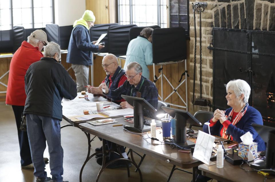 Poll workers check the IDs of voters Tuesday at the Whiting Boathouse in Neenah.