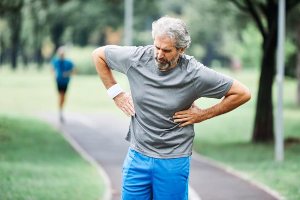 portrait of a senior man exercising and running outdoors having cardio problems chest pain