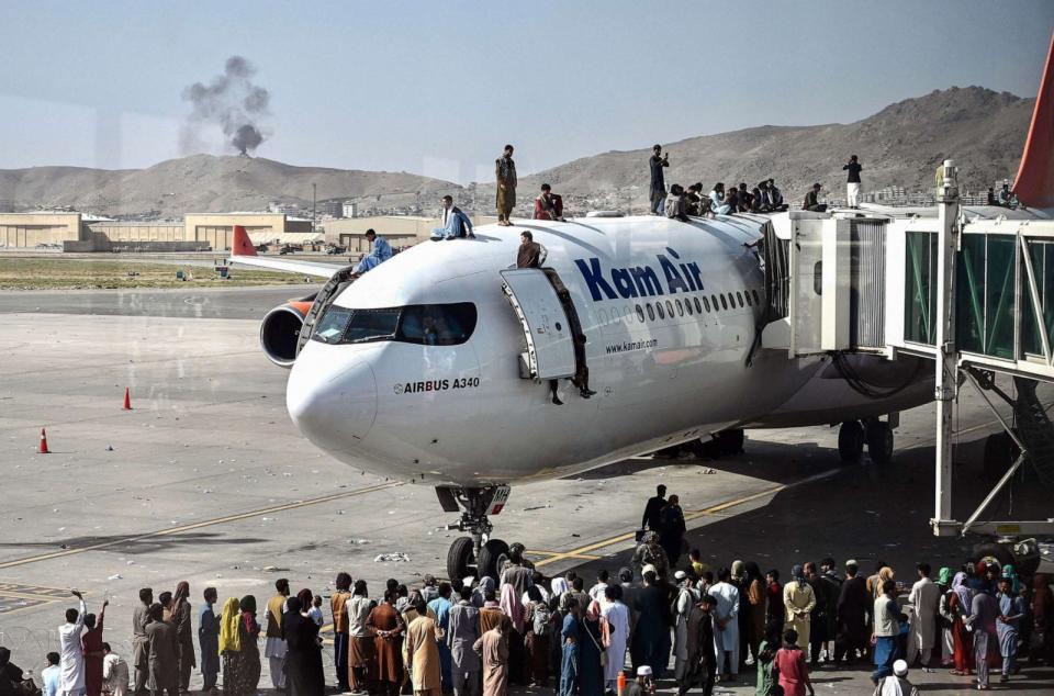 PHOTO: Afghan people climb atop a plane as they wait at the Kabul airport, Aug. 16, 2021, after a swift end to Afghanistan's 20-year war, as thousands of people mobbed the city's airport trying to flee the group's feared hardline brand of Islamist rule. (Wakil Kohsar/AFP via Getty Images, FILE)