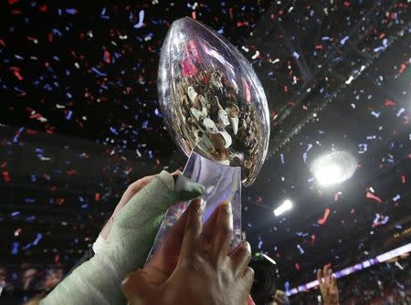 Members of the New England Patriots hold up the Vince Lombardi Trophy after defeating the Seattle Seahawks in the NFL Super Bowl XLIX football game in Glendale, Arizona, February 1, 2015. REUTERS/Lucy Nicholson