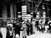 A stunned crowd gathers in front of the The New York Sun's building on Broadway, New York City, to read the bulletin board declaring that the Titanic had sunk.