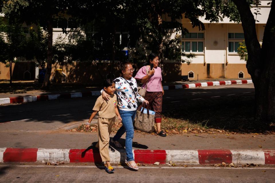 Two women and a girl walk away from a building in Thailand.