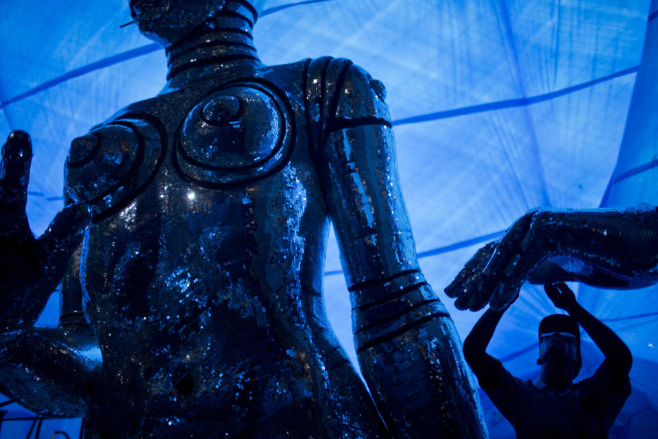 In this photo taken Tuesday, Jan. 22, 2013, a man works on a Carnival float sculpture at the Grande Rio Samba school in Rio de Janeiro, Brazil. Yet it's from warehouses like this one that Rio's over-the-top glitz-and-glam Carnival parades emerge, as they will Monday night for the final round of a two-day performance. The internationally renowned competition between 12 elite samba groups dazzles more than a billion spectators in person and on TV for two days, but it takes nearly a year and hundreds of workers, many of them volunteers, to pull each one together. (AP Photo/Felipe Dana)