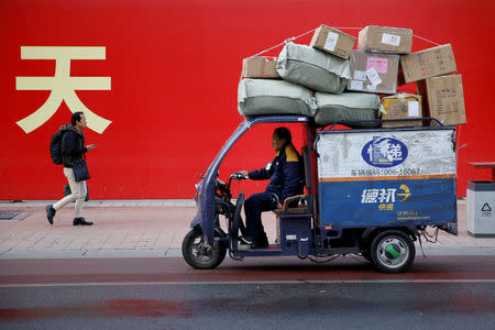 FILE PHOTO: An electric delivery vehicle of Deppon Logistics drives past a banner with a government slogan in Beijing, November 6, 2018. REUTERS/Thomas Peter/File Photo