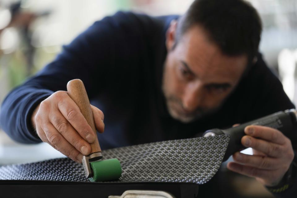 A worker fixes an anti-slip pool surface at the Myrtha Pools factory, in Castiglione delle Stiviere, northern Italy, Tuesday, March 12, 2024. Italian company Myrtha Pools is producing 24 pools for the Paris Olympics at its factory in Castiglione delle Stiviere, near Verona. The pools will be used for swimming, diving, water polo, artistic swimming and training areas in Paris. It's the sixth Olympics that Myrtha will be providing pools for. (AP Photo/Luca Bruno)