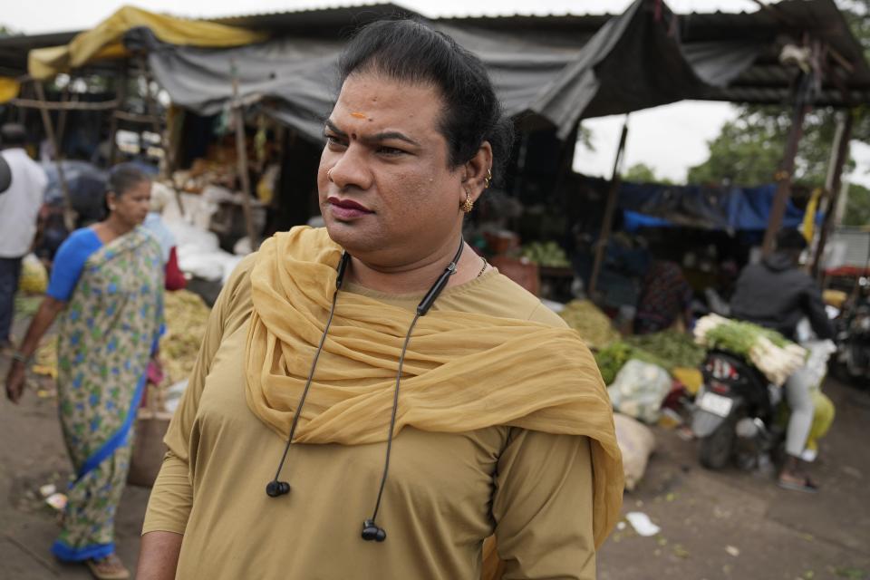 Preethi, a 38-year-old transgender woman who uses only her first name, looks for customers to ferry in her electric auto rickshaw at a vegetable market in Bengaluru, India, Wednesday, July 12, 2023. She's now one of millions of electric vehicle owners in India, but one of very few to have received an EV through a charitable donation. (AP Photo/Aijaz Rahi)