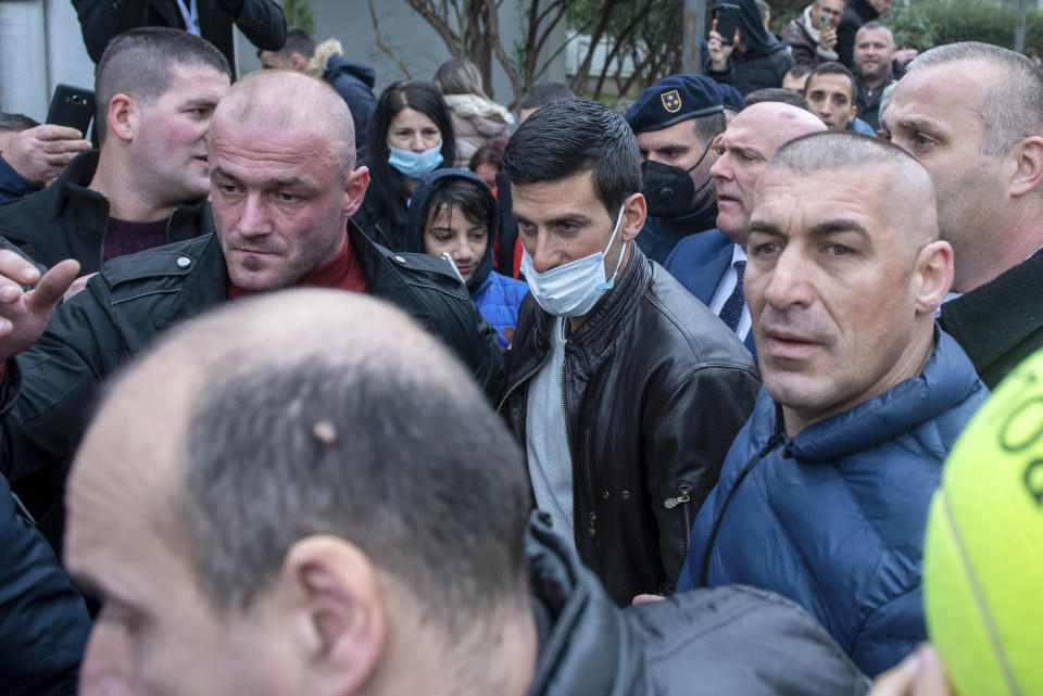 Serbian tennis player Novak Djokovic, center, wearing a face mask, arrives in the municipal building in Budva, Montenegro, Friday, Jan. 28, 2022. Djokovic arrived to receive a plaque declaring him an honorary citizen of the town. (AP Photo/Risto Bozovic)